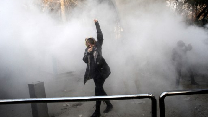 O studentă a Universității din Teheran se ferește de gazele lacrimogene trase de poliția iraniană &icirc;n urma protestelor anti-guvernamentale ale studenților.