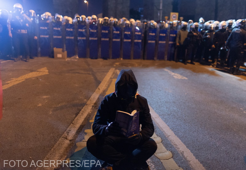 Un demonstrant citește o carte în fața forțelor de ordine care blochează accesul în piața Taksim din Istanbul, 22 martie 2025.